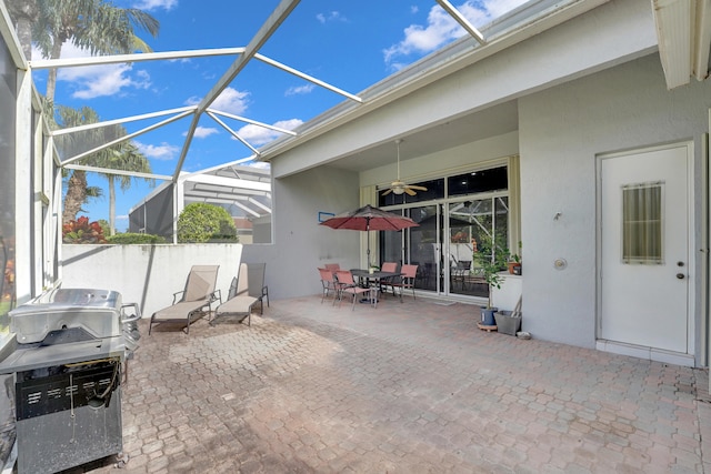 view of patio featuring ceiling fan, a grill, and glass enclosure