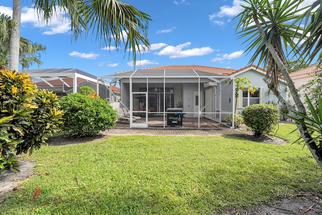 rear view of property with a yard, a patio area, and glass enclosure