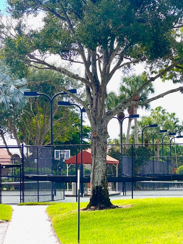 view of tennis court featuring a yard