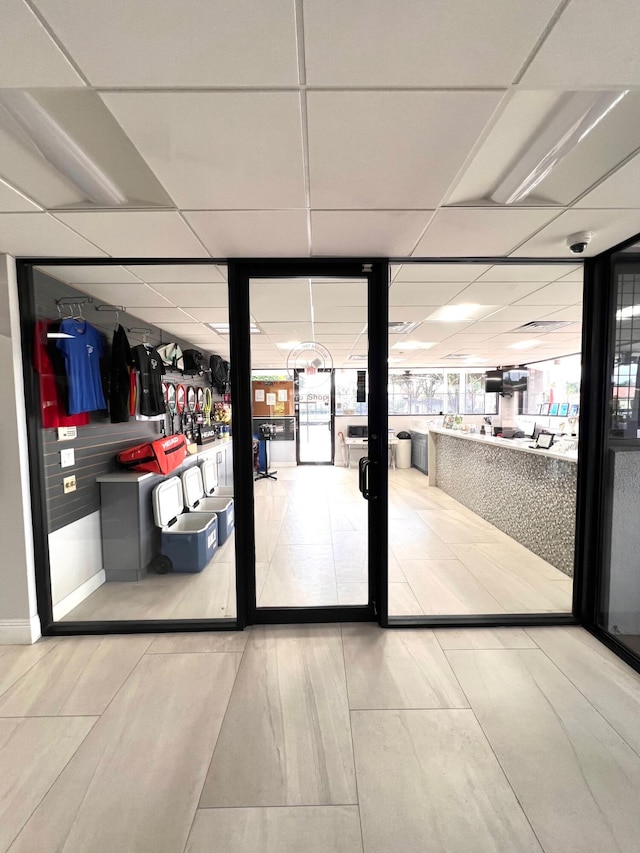 doorway to outside featuring a drop ceiling and floor to ceiling windows