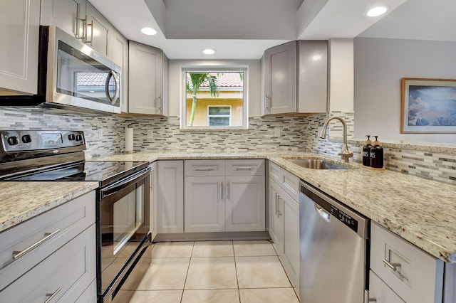 kitchen with light stone countertops, sink, stainless steel appliances, gray cabinets, and light tile patterned floors