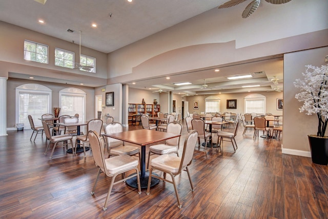 dining room featuring dark hardwood / wood-style floors, ceiling fan, and a towering ceiling