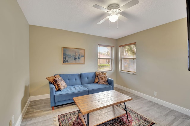 living room featuring a textured ceiling, light hardwood / wood-style flooring, and ceiling fan