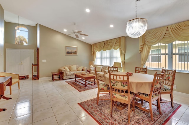 dining area with ceiling fan with notable chandelier, light tile patterned floors, and vaulted ceiling