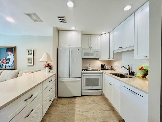 kitchen with white cabinetry, sink, kitchen peninsula, backsplash, and white appliances