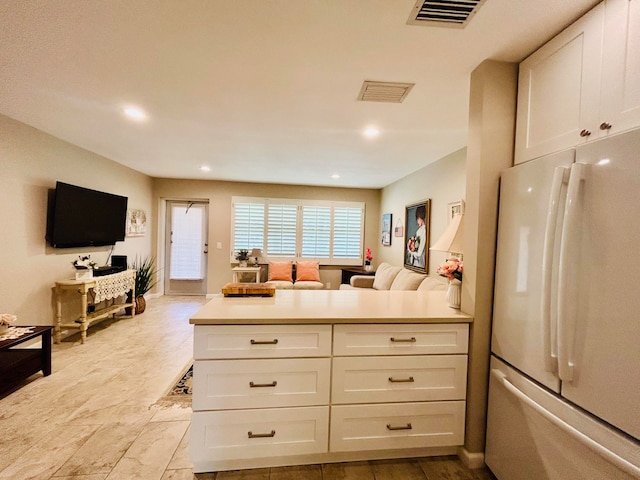 kitchen featuring fridge and white cabinetry