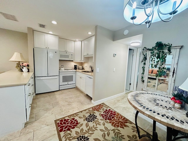 kitchen with backsplash, pendant lighting, sink, white cabinets, and white appliances