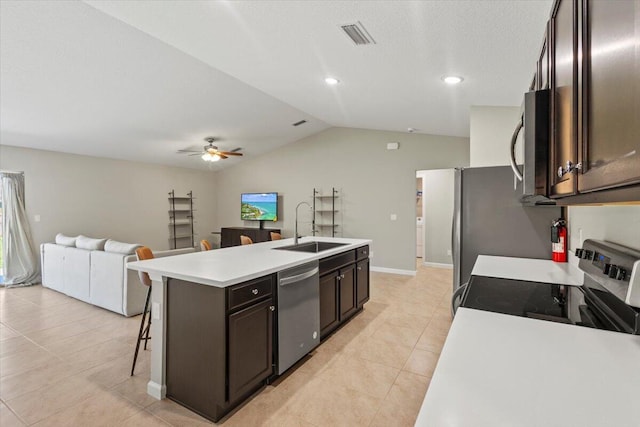 kitchen featuring lofted ceiling, a kitchen island with sink, dark brown cabinets, stainless steel appliances, and sink