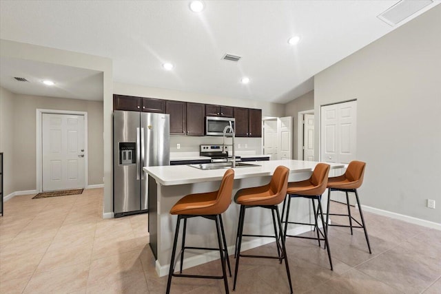 kitchen with a breakfast bar area, vaulted ceiling, a kitchen island with sink, and stainless steel appliances