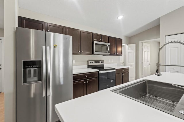 kitchen featuring sink, vaulted ceiling, dark brown cabinets, and stainless steel appliances