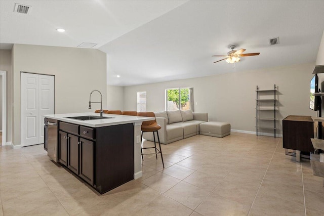 kitchen featuring dishwasher, a kitchen island with sink, sink, vaulted ceiling, and light tile patterned floors