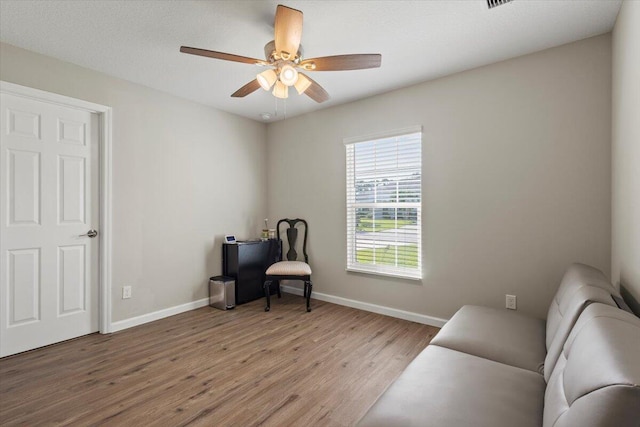 living area with hardwood / wood-style floors and ceiling fan