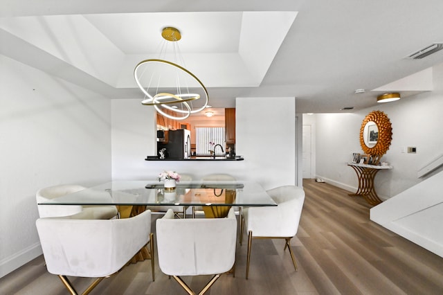 dining room with a notable chandelier, hardwood / wood-style flooring, and a tray ceiling