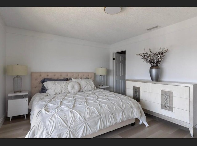 bedroom featuring hardwood / wood-style floors and a textured ceiling