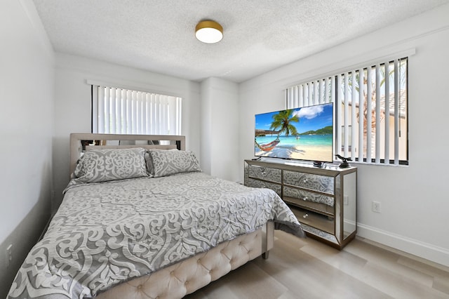 bedroom with a textured ceiling and light wood-type flooring