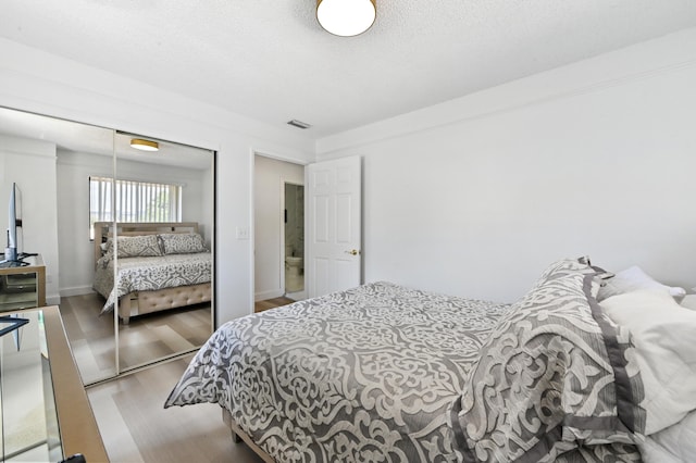 bedroom featuring light hardwood / wood-style flooring, a textured ceiling, and a closet