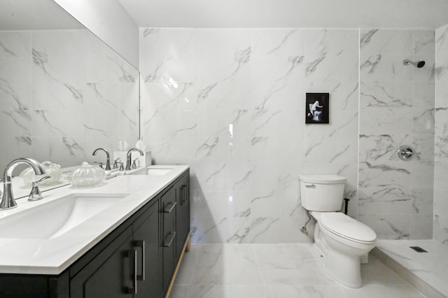 bathroom with a tile shower, vanity, toilet, and tile walls