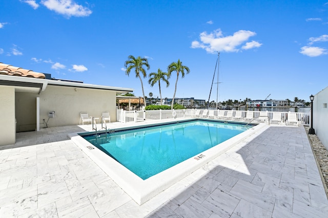 view of swimming pool featuring a patio and a water view