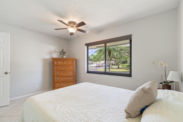 bedroom with a textured ceiling, light tile patterned floors, and ceiling fan