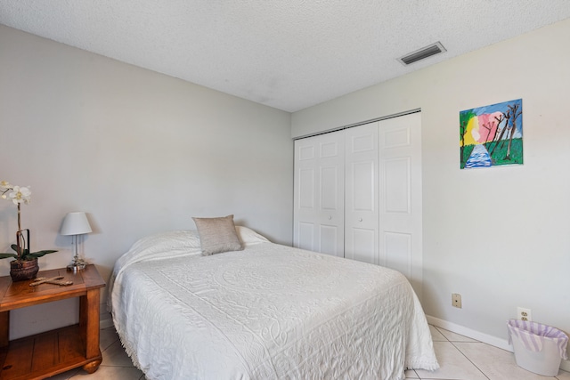 tiled bedroom with a textured ceiling and a closet