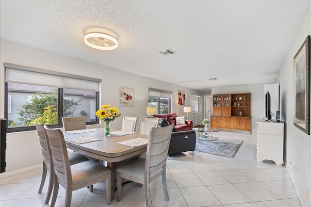 dining area featuring a textured ceiling, a healthy amount of sunlight, and light tile patterned floors