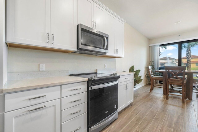 kitchen with appliances with stainless steel finishes, light hardwood / wood-style flooring, white cabinets, and light stone countertops