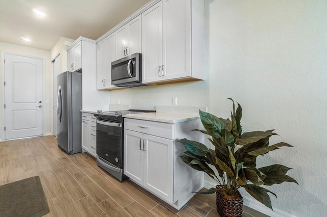 kitchen featuring appliances with stainless steel finishes, white cabinetry, and light wood-type flooring