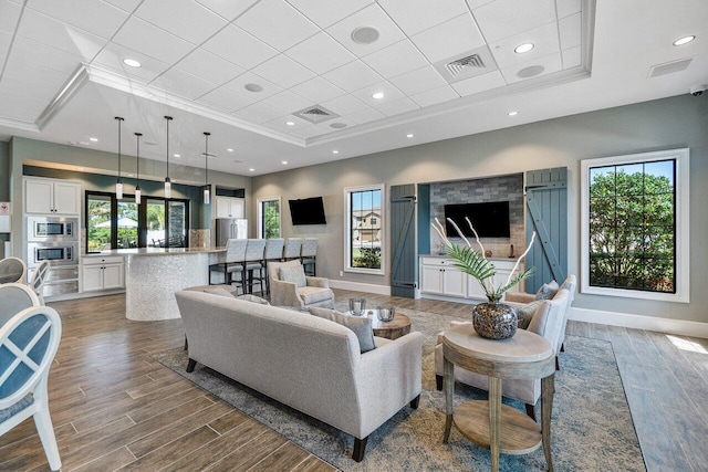 living room featuring ornamental molding, wood-type flooring, and a tray ceiling