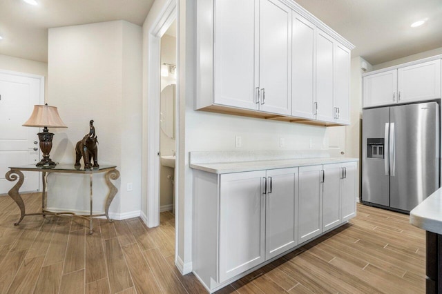 kitchen featuring light hardwood / wood-style floors, stainless steel fridge with ice dispenser, and white cabinets