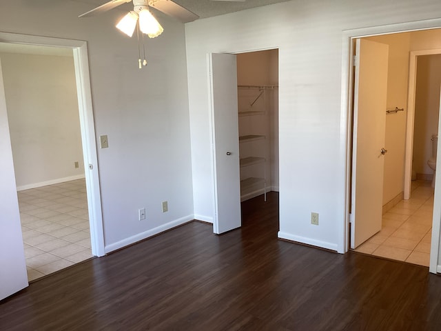 unfurnished bedroom with hardwood / wood-style flooring, ensuite bathroom, ceiling fan, a spacious closet, and a closet