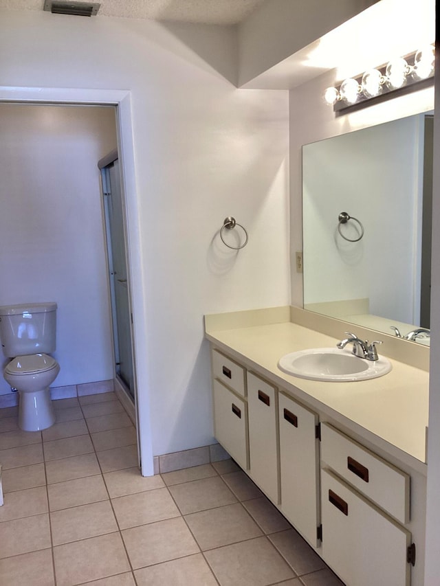 bathroom featuring toilet, vanity, a textured ceiling, and tile patterned flooring