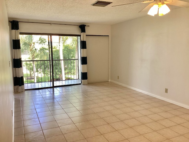 tiled empty room with ceiling fan and a textured ceiling