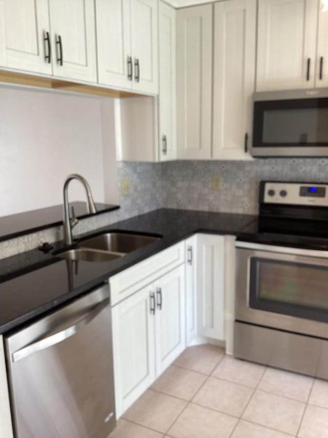 kitchen featuring stainless steel appliances, backsplash, light tile patterned floors, sink, and white cabinets