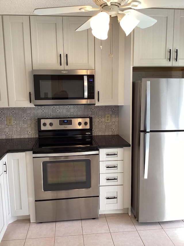 kitchen featuring ceiling fan, light tile patterned floors, backsplash, and appliances with stainless steel finishes