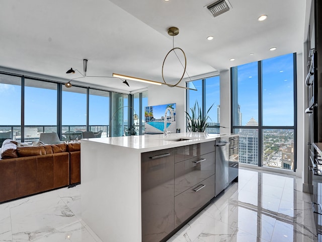 kitchen with dishwasher, a kitchen island with sink, sink, decorative light fixtures, and a wall of windows