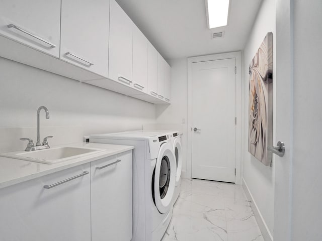 laundry area with washing machine and dryer, cabinets, and sink