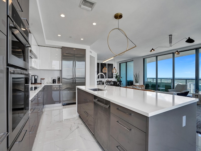 kitchen with appliances with stainless steel finishes, sink, a large island, pendant lighting, and white cabinets