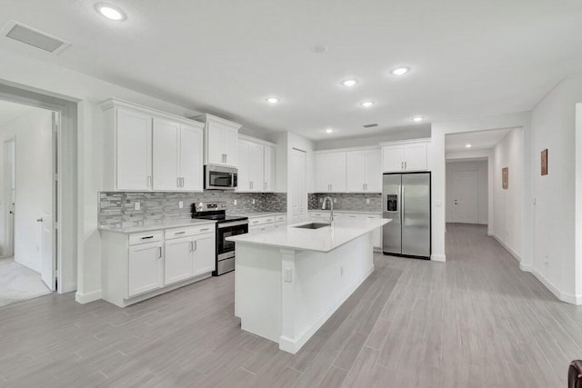 kitchen with sink, light hardwood / wood-style flooring, an island with sink, white cabinets, and appliances with stainless steel finishes