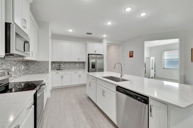 kitchen with an island with sink, stainless steel appliances, white cabinetry, and sink