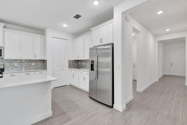 kitchen featuring tasteful backsplash, light hardwood / wood-style flooring, white cabinets, and stainless steel appliances