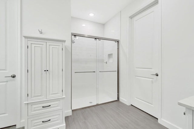 bathroom with a shower with door and hardwood / wood-style floors