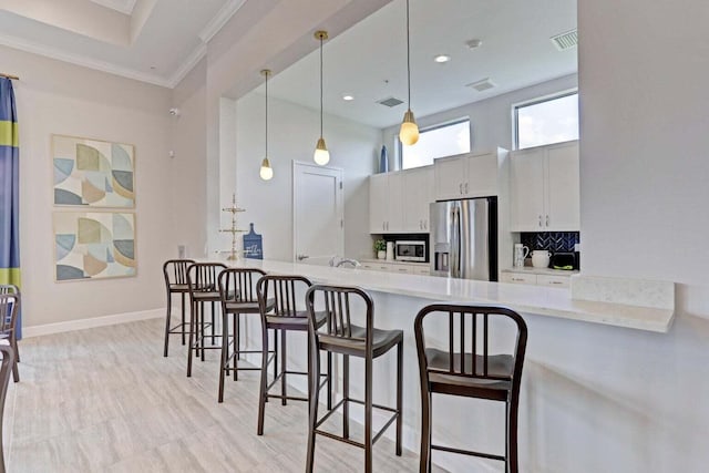 kitchen with light stone countertops, appliances with stainless steel finishes, decorative light fixtures, and white cabinetry