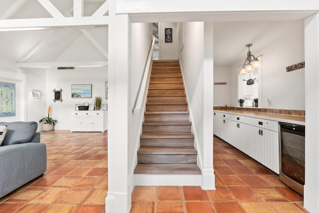 stairway with beamed ceiling and an inviting chandelier