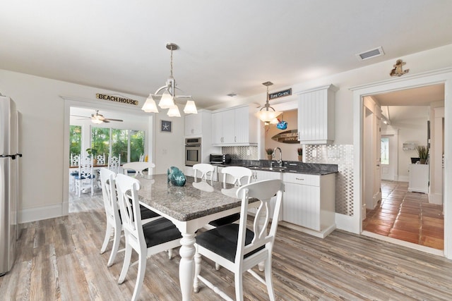 dining area featuring ceiling fan with notable chandelier and light hardwood / wood-style flooring