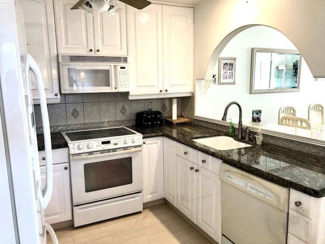 kitchen featuring sink, dark stone countertops, white appliances, white cabinets, and light wood-type flooring