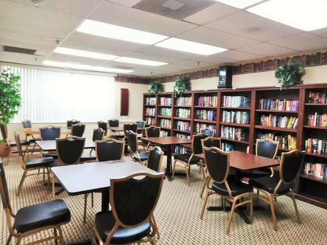 interior space with a paneled ceiling and bookshelves