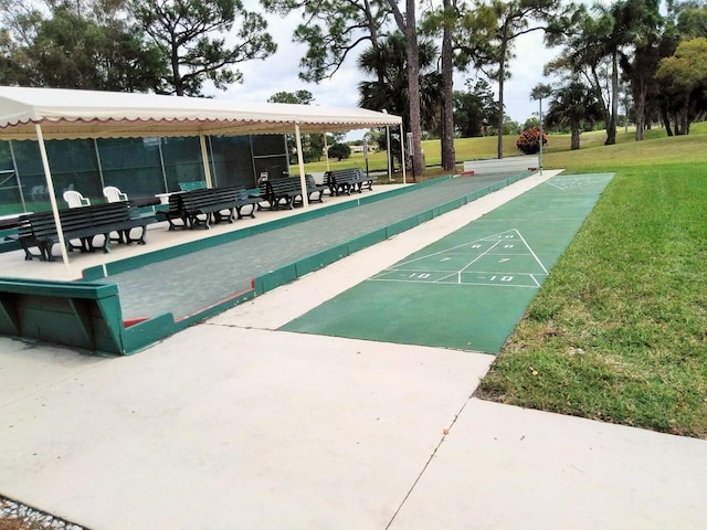 view of home's community with shuffleboard and a yard