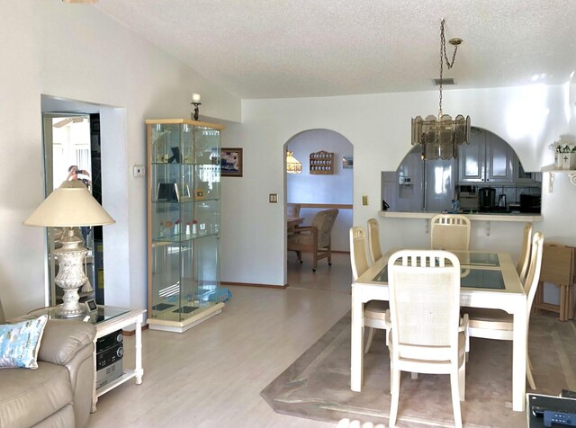 7633 S Tahiti Ln Unit 204, Lake Worth, FL 33467 - dining area featuring a textured ceiling, arched walkways, a chandelier, wood finished floors, and lofted ceiling
