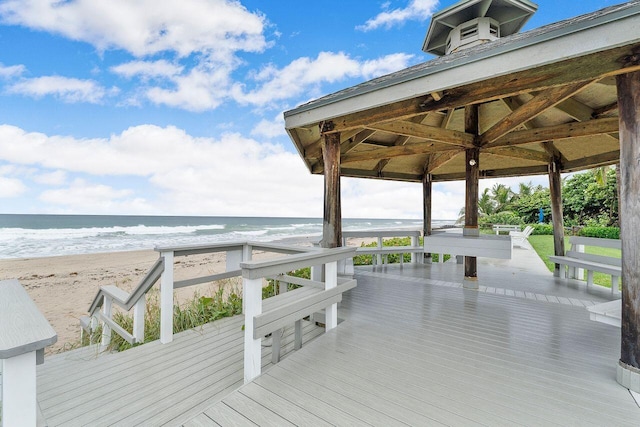 wooden deck featuring a gazebo, a water view, and a view of the beach