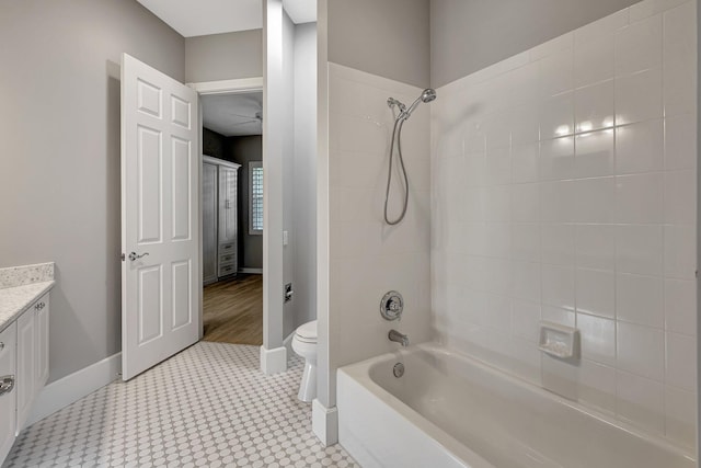 full bathroom with ceiling fan, vanity, toilet, and tiled shower / bath